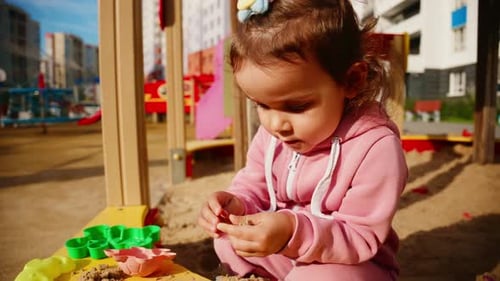 Jeune enfant engagé dans un jeu créatif dans un bac à sable en utilisant des jouets colorés pour construire et explorer en s'amusant