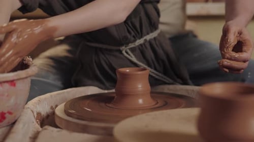 A Middle Aged Man Potter Works in a Workshop Together with Son Uses a Rotating Pottery Wheel to Mold