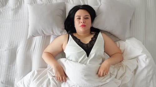 Smiling Brunette Woman Lying in Bed Relaxing