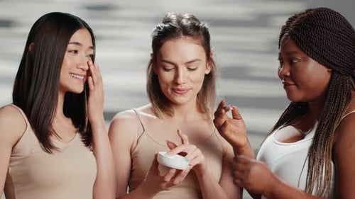 Diverse Young Women Applying Skin Cream Together