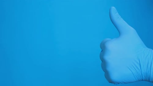 Hand in Blue Gloves Shows Thumb Up Isolated on Blue Background Man Shows Gesture