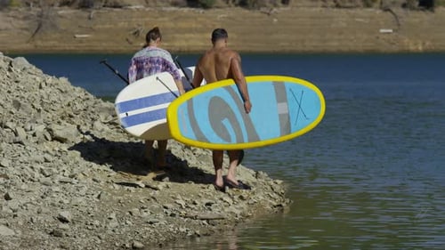 Couple Walking by Lake with Stand Up Paddle Boards Activity