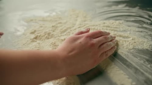 professional chef throws flour on table stirs it before preparing bread pastry in bakery