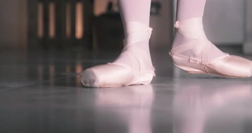 Close up of ballet dancer feet as she practices doing a lift in a dance studio. Woman's feet in poin