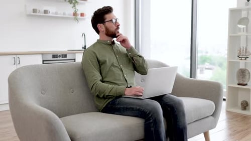 Man Working on Laptop at Home on Sofa