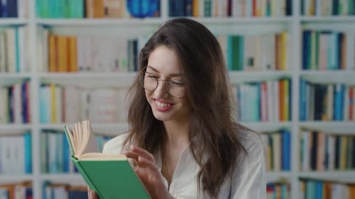 Eine Frau mit Brille ist in einer ruhigen Bibliothek in ein Buch vertieft