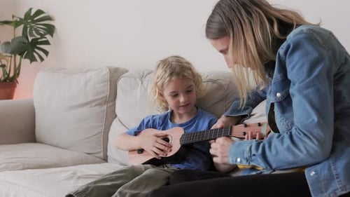 Boy Learning Ukulele with Help from Adult