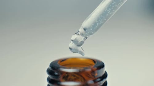 Liquid Being Dispensed From Glass Dropper into Bottle