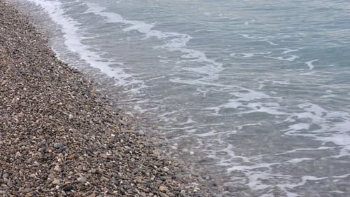 Beautiful view of wavy sea and pebbles on beach