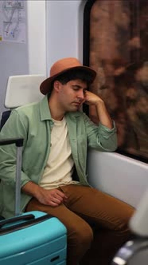 voyageur épuisé à la verticale endormi à côté de ses bagages dans le train rentrant chez lui après un long voyage