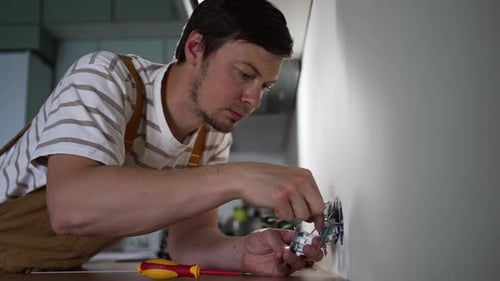 Professional Electrician Installing Electrical Sockets in Contemporary Kitchen Performing Precise