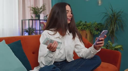 Woman with Money Using Phone at Home