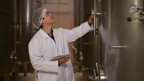 Vigneron professionnel contrôlant le processus de fabrication et la qualité du vin dans une usine vinicole
