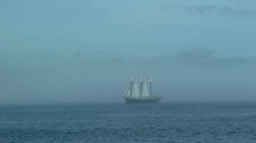 Großes segelndes Piratenschiff in der Ferne auf See, umgeben von Nebel und Nebel im Meer