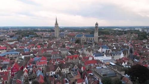 Rising up above city center of Bruges with two large gothic towers, aerial HD