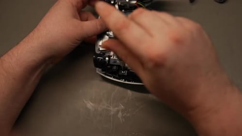 Professional Technician Repairing Gaming Controller Using Screwdriver with Precision While