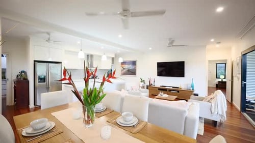Fully staged dininng kitchen area of white earthy neutral tone open plan luxurious home. Interior of