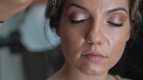 Makeup Artist Applying Eyeliner to Woman's Eyelid