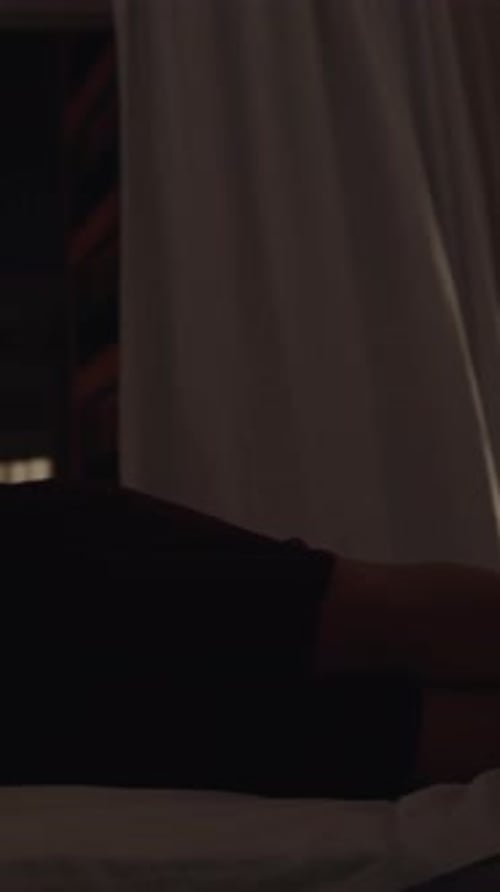 Woman Rests in Bed Looking at a Phone