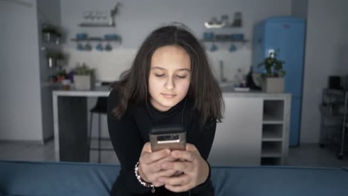 Teenage Girl Using Smartphone on a Couch at Home