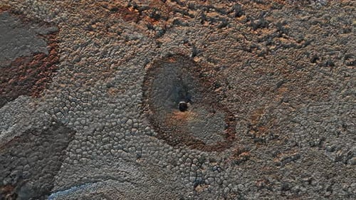 Boiling mud volcanoe pond with colorful textures and pattern around