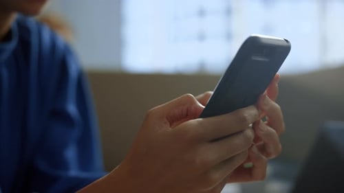 African American Businesswoman Texting Message on Smartphone at Office Workplace. Closeup Focused