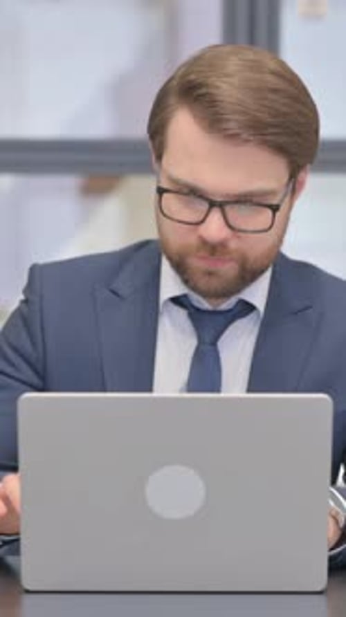 Man in Suit Working on Laptop During Video Call