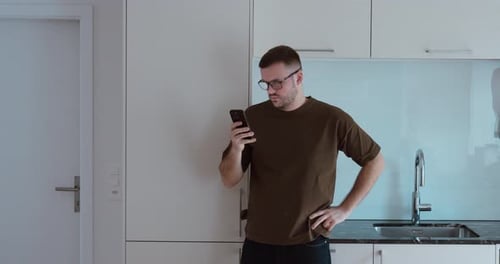 Man Using Smartphone in Modern White Kitchen