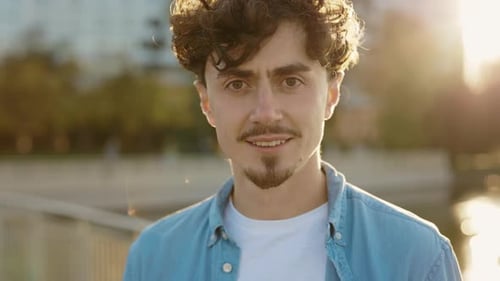 Portrait of a Young Student Standing in the Park Smiling and Looking at Camera with Beard Real