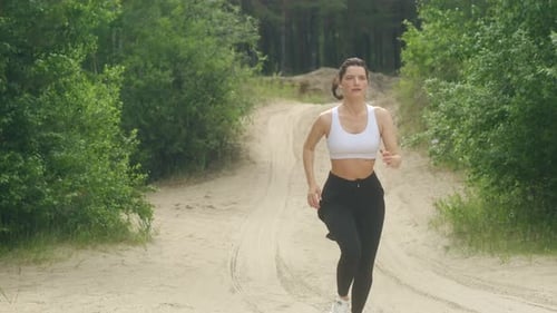 Woman Running on a Sandy Path in a Forest