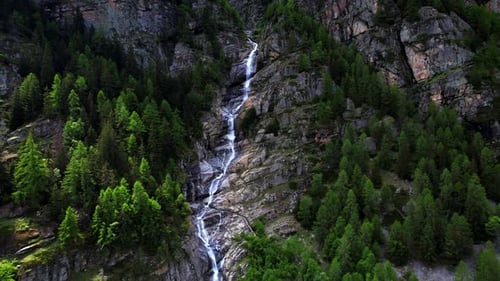 4k Drone Flys Backward Revealing Scale Of Cascading Waterfall Nestled In between Mountain Landscape