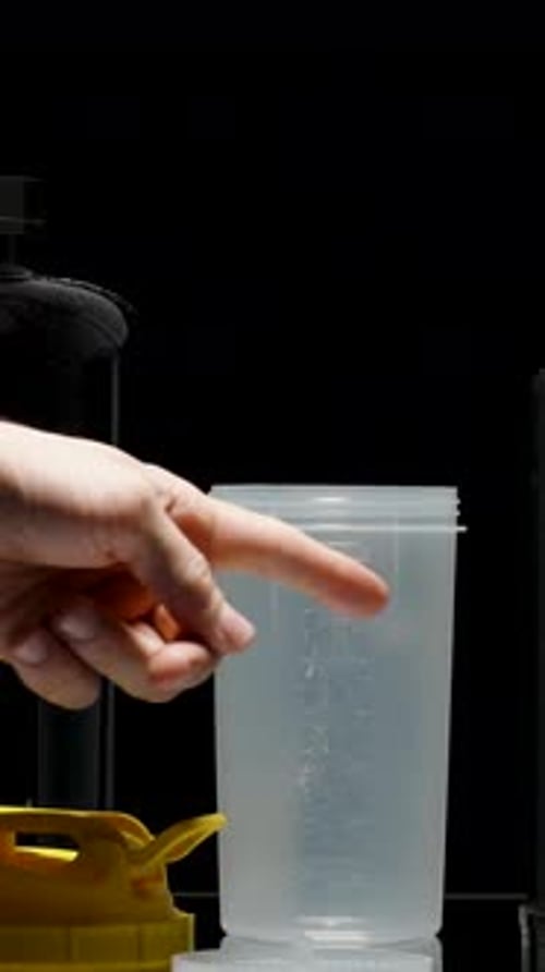 Vertical video. A Variety Of Black Cans Of Sports Nutrition, A Man Points His Finger And Chooses One