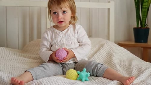 Sweet Child Playing with Tactile Balls on Bed