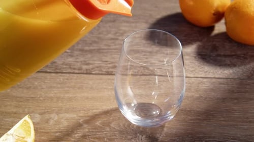 Pouring Fresh Orange Juice Into a Clear Glass