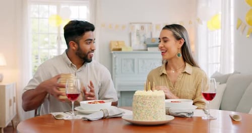 Interracial, couple and celebrate for birthday with gift, being happy and relax together at party