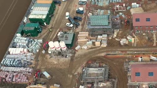 Construction, aerial swivel shot of Red Digger moving around site. New build site 60fps