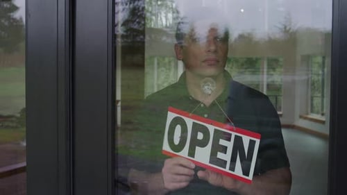 Small business owner stands sadly holding closed sign after covid pandemic