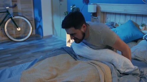 Un homme s'étire dans une chambre à coucher légèrement éclairée créant une ambiance apaisante et paisible
