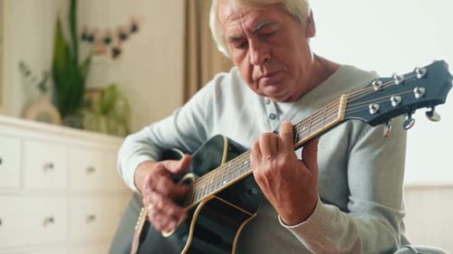 Senior Man Plays Acoustic Guitar Inside Home