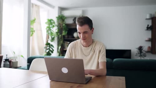 Young Man Works at Laptop on Table