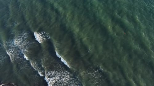 Aerial top view powerful waves on blue turquoise ocean crashing and foaming. Drone 4K footage sunny