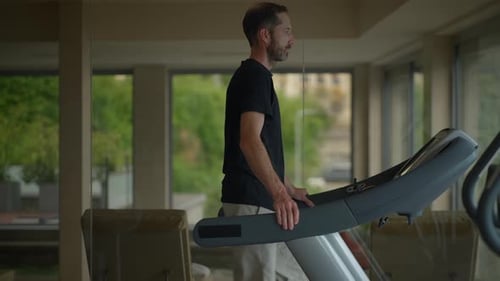 A Man is Exercising Diligently on an Elliptical Machine in a Contemporary Gym Setting