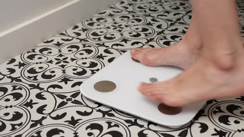 Woman Checking Her Weight on Weighing Scales in Bathroom