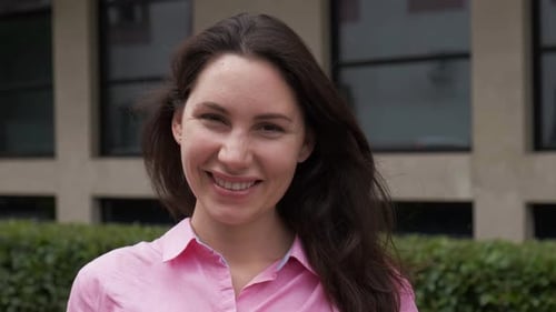 Woman Standing Against the Business Building Smiling Straightening Her Hair