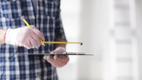 Man taking notes on clipboard with measuring ruler during home repair job