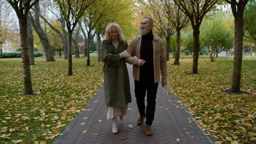 Senior romantic couple walking in autumn park enjoying relaxed atmosphere together