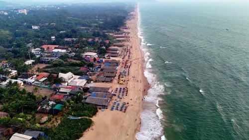Grande vue aérienne cinématographique d'une plage animée avec des chaises longues à motifs, des amateurs de plage éparpillés et