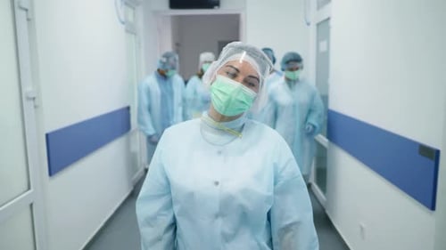 Tired Team of Doctors in Protective Suits After Hurd Operarion Medical Workers Masked Walk Down the