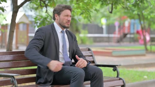 Businessman Sitting on Park Bench with Back Pain