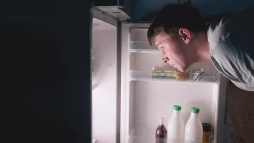 Young Adult Opening Refrigerator to Grab Lettuce